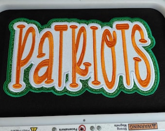 May include: Embroidered patch with the word "PATRIOTS" in orange, outlined in white and green. The patch is on a black background, and the text is in a bold, stylized font. The patch is likely for apparel or accessories.