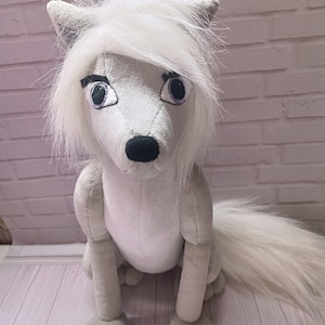 May include: A white ceramic mug with a black handle and the text "But First, Coffee" in a bold, black font. The mug is set against a blurred background, suggesting a cosy setting.