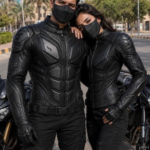 Puede incluir: Una chaqueta de motocicleta negra con placas de protección integradas en el pecho y los hombros, con cuello alto, cremallera frontal completa y paneles texturizados. La chaqueta se combina con guantes negros a juego y una mascarilla.