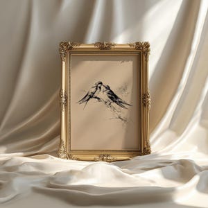 May include: A framed artwork featuring a pen and ink drawing of two birds perched on a branch. The artwork is set within an ornate, gold-colored frame. The background is a neutral beige color.