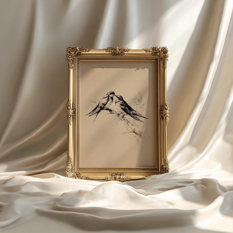 May include: A framed artwork featuring a pen and ink drawing of two birds perched on a branch. The artwork is set within an ornate, gold-colored frame. The background is a neutral beige color.