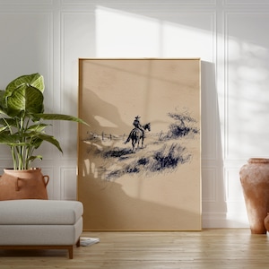 K&ouml;nnte beinhalten: Ein gerahmter Druck mit einer Feder- und Tinte-Illustration eines Cowboys auf einem Pferd. Das Kunstwerk zeigt einen einsamen Reiter, der eine grasbewachsene Landschaft durchquert, mit einem Zaun und sp&auml;rlicher Vegetation. Die Farbpalette ist neutral, mit Braun- und Schwarzt&ouml;nen.