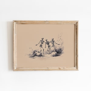 May include: A framed art print featuring a dark ink illustration on a tan background. The image depicts three skeletons dancing among several pumpkins in a field. The skeletons are shown in various poses, and the pumpkins are scattered on the ground.