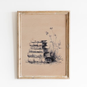 May include: A framed pen and ink illustration of a stack of books next to tall grass and wildflowers. The artwork is in a gold-colored frame and has a neutral background.