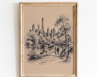 May include: A framed ink drawing on tan paper depicting a city skyline viewed from a park. The scene features a path with two figures walking, a stone bridge over water, trees, a lamp post, and a bench, all rendered in detailed black lines.