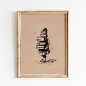 May include: Framed black and white print of a young child carrying a stack of books. The artwork is a sketch-style illustration with a neutral background and a gold-colored frame.