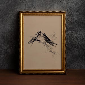 May include: A framed artwork featuring a pen and ink drawing of two birds perched together. The birds are depicted in black against a cream-colored background. The frame is gold with a beaded edge, adding a touch of elegance to the piece.