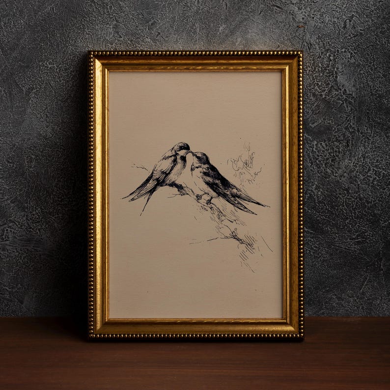 May include: A framed artwork featuring a pen and ink drawing of two birds perched together. The birds are depicted in black against a cream-colored background. The frame is gold with a beaded edge, adding a touch of elegance to the piece.