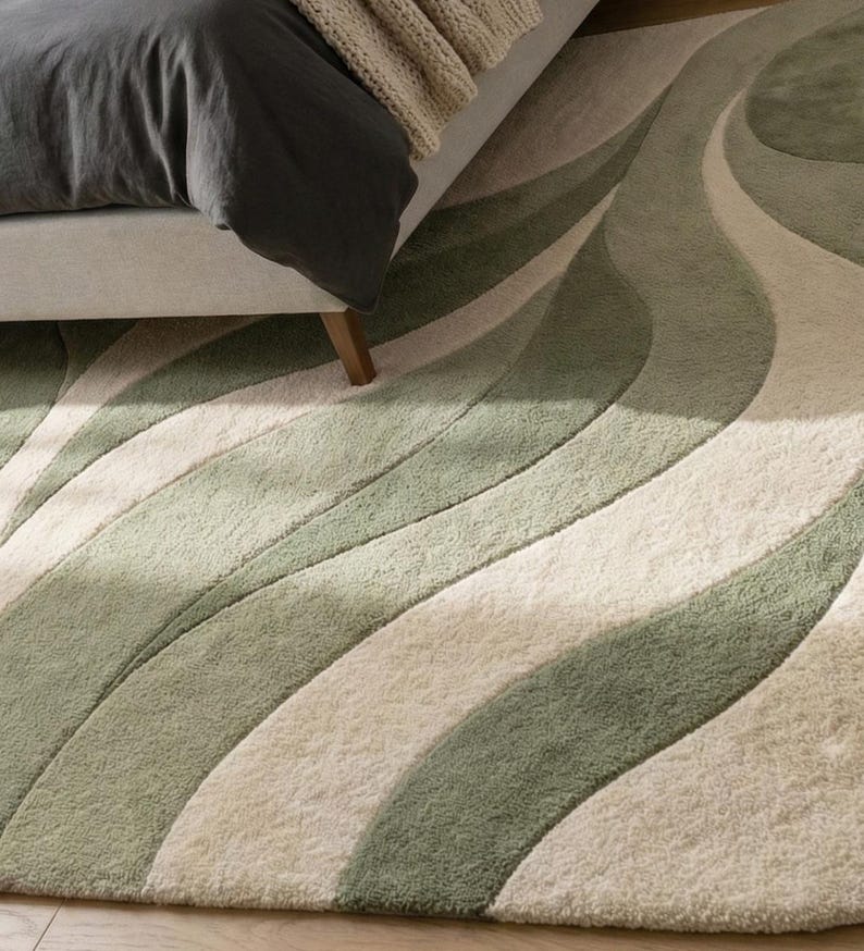 May include: A patterned rug with a flowing, wave-like design. The rug features alternating stripes of light green, medium green, and off-white. The rug is placed near a bed with a grey duvet cover and a beige throw.