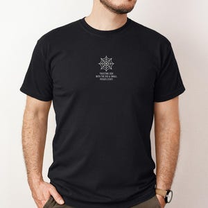 May include: A black short-sleeved t-shirt featuring a white graphic of a spider web centered on the chest. Below the web, the text reads: TRUSTING GOD WITH THE BIG & SMALL POTATO STUFF. The shirt has a crew neckline and a standard fit.
