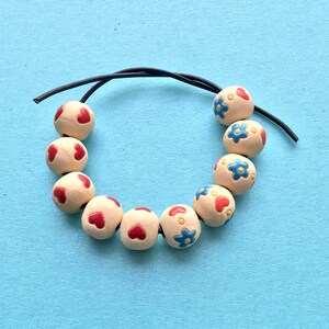 Heart or hearts and flower decorated ceramic beads from Golem studio