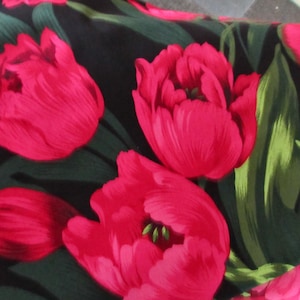 May include: A black fabric with a repeating pattern of pink tulips and green leaves.