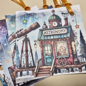May include: Watercolor illustration of astronomy-themed gift tags. The tags feature a detailed depiction of an astronomy building with a telescope, clock tower, and the word "ASTRONOMY". The tags are tied with gold ribbons.