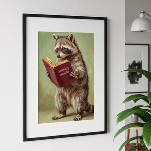 May include: Framed art print featuring a raccoon reading a book with the words "Stealing Snacks" on the cover. The raccoon is depicted in a realistic style with a green background.