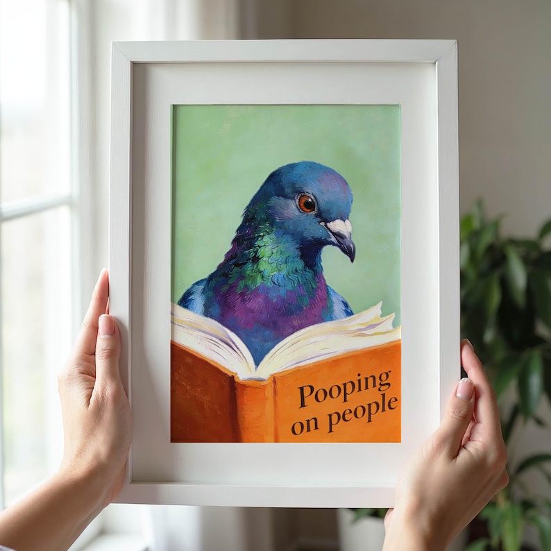 May include: A framed print featuring a colorful pigeon reading a book with the title "Pooping on people." The pigeon has iridescent blue, green, and purple feathers. The book is open, with orange covers and white pages against a green background.