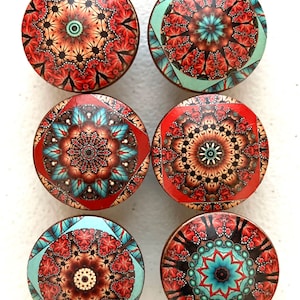 May include: Six round, decorative cabinet knobs with a mandala design. The knobs feature a mix of red, orange, brown, black, and turquoise colors.