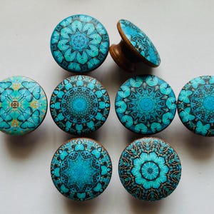May include: Eight decorative round knobs with a blue and gold mandala design. The knobs are made of wood and have a smooth finish.