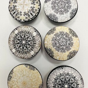 May include: Six round ceramic knobs with black and white mandala designs. The knobs have a black border and a white background with black and gold designs.