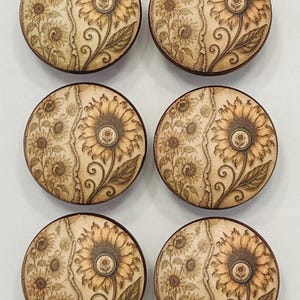 May include: Six circular wooden buttons arranged in two columns. Each button features a laser-engraved sunflower design with a split composition, showing a large detailed sunflower on the right and smaller sunflower clusters on the left.