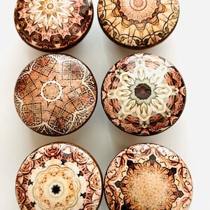 May include: Six round wooden knobs with intricate mandala designs in shades of brown, beige, and white.
