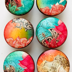 May include: Six round wooden knobs with colorful floral designs. The knobs feature a variety of colors, including orange, yellow, green, blue, and red. The designs are intricate and detailed, and they would add a touch of whimsy to any piece of furniture.