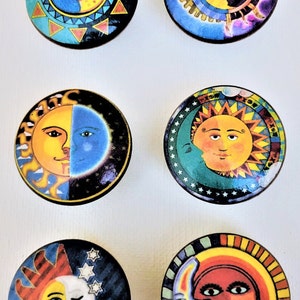 May include: Six round wooden ornaments with colorful sun and moon designs. Each ornament features a different design with a sun and moon face.