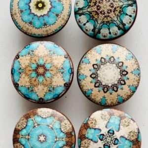 May include: Six round, decorative knobs with intricate mandala designs in shades of blue, brown, and beige. The knobs have a wooden base and are perfect for adding a touch of bohemian style to furniture.