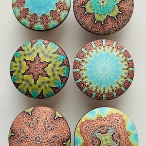 May include: Six round wooden knobs with colorful mandala designs. The knobs feature intricate patterns in shades of blue, green, yellow, and brown.