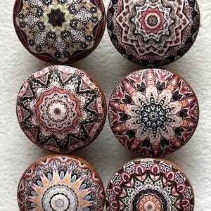 May include: Six round wooden knobs with intricate mandala designs in shades of brown, beige, pink, and black.