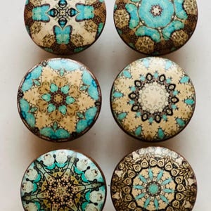 May include: Six round wooden knobs with intricate mandala designs in shades of brown, beige, blue, and turquoise.