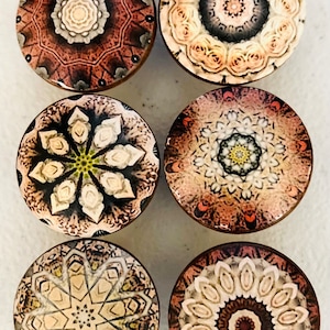 May include: Six round, decorative knobs with intricate mandala designs. The knobs are made of wood and have a brown, beige, and white color scheme.
