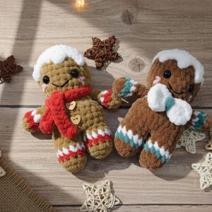 May include: Two handmade crochet gingerbread men with white icing, red scarves, and button details. Accompanying the gingerbread men are decorative star ornaments, perfect for holiday decor.