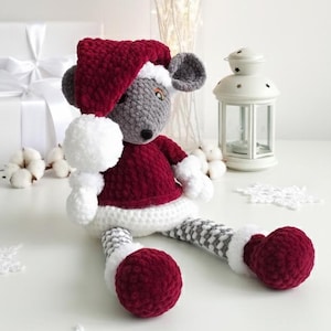 Puede incluir: Muñeca de ratón de ganchillo hecha a mano con gorro de Papá Noel burdeos y atuendo a juego. La muñeca tiene orejas grises, un pompón blanco y piernas a rayas grises y blancas. Decoración festiva navideña.