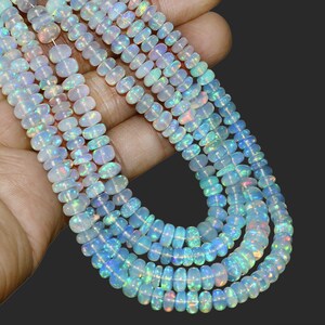 May include: Strands of iridescent opal beads. The beads are a mix of white and translucent colors, with flashes of blue, green, and pink. The beads are strung together, creating a necklace.