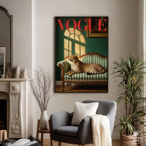 Op de afbeelding: Een ingelijste Vogue-magazinecover met een cheetah die rust op een groen en wit gestreepte bank. Het woord "VOGUE" is rood. Het kunstwerk wordt tentoongesteld in een woonkamer met een grijze fauteuil en een kamerplant.