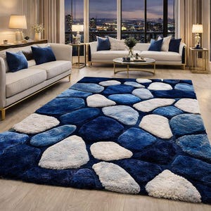 May include: A rectangular area rug featuring a textured, three-dimensional pattern of irregular, pebble-like shapes in varying shades of deep navy blue, light blue, and off-white, creating a high-pile surface that mimics a stone-covered floor.