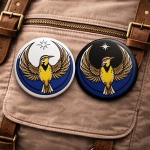 May include: Two round pinback buttons featuring a stylized bird design. One button has a white background with a blue border, the other has a black background with a blue border. Both buttons have a star and a bird with yellow, brown, and blue colors.