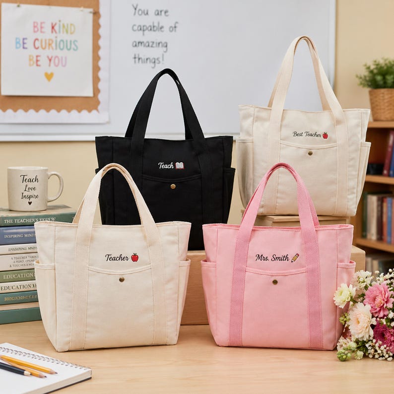 May include: Four canvas tote bags in black, cream, and pink, with side pockets and handles. Each bag is embroidered with text: "Teach," "Teacher," "Best Teacher," and "Mrs. Smith." The bags have a button closure.