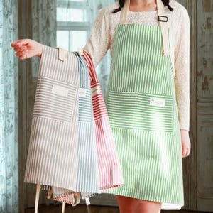 May include: A selection of striped aprons in shades of green, grey, blue, and red. Each apron has a large front pocket and a blank label. The aprons feature cream-coloured straps and are suitable for kitchen or craft activities.