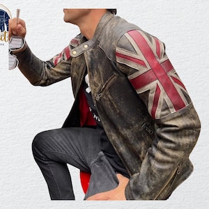 May include: A distressed brown leather jacket with a Union Jack flag design on the right sleeve. The jacket has a zipper closure and a classic biker style. The logo "Quality One Jackets" is visible in the upper left corner.