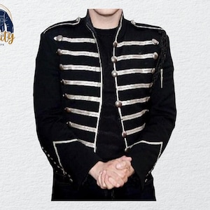 May include: Black military-style jacket with silver-colored trim and buttons. The jacket features multiple horizontal stripes across the chest and sleeves. The jacket has a high collar and decorative shoulder accents. The logo "Quality One Jackets" is in the upper left corner.