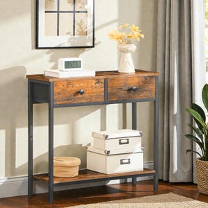 May include: A console table with a distressed wood effect top and drawers, supported by a dark grey metal frame. The table features two drawers and a lower shelf. It is decorated with a vase of yellow flowers, a clock, and two white storage boxes.