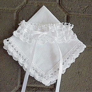 May include: A white lace handkerchief with a satin ribbon tied in a bow. The handkerchief has a delicate lace trim around the edges.