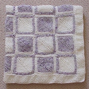 May include: A white and purple knitted baby blanket with a checkered pattern.