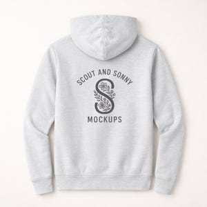 Puede incluir: Una sudadera con capucha gris claro con capucha y mangas largas. La parte trasera de la sudadera presenta un diseño circular con el texto "SCOUT AND SONNY" encima de una "S" floral y la palabra "MOCKUPS" debajo.