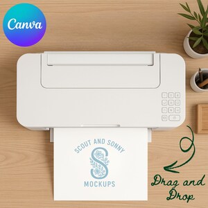 May include: A white printer with a paper output showing the text "SCOUT AND SONNY MOCKUPS" in blue. The image is on a light brown wooden surface, with a small plant and pencils in the background. The word "Canva" is in a blue and purple circle.