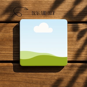 May include: A square graphic with a blue sky, white cloud, and green hills. The text "DRAG AND DROP" is displayed in black letters. The image is set against a wooden background.