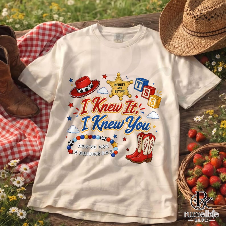 May include: A cream-colored t-shirt featuring a graphic print with the text I Knew It, I Knew You, a red cowboy hat, a yellow sheriff star with the text INFINITY AND BEYOND, blue and red blocks, a beaded bracelet, and red cowboy boots.