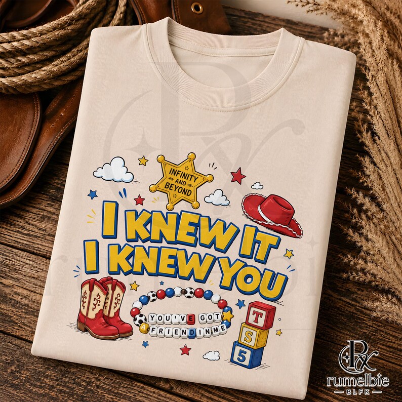 May include: A beige t-shirt featuring a graphic print with the text I KNEW IT I KNEW YOU, a yellow sheriff star with INFINITY AND BEYOND, a red cowboy hat, a pair of red and beige cowboy boots, a beaded bracelet with YOU'VE GOT A FRIEND IN ME, and blocks.