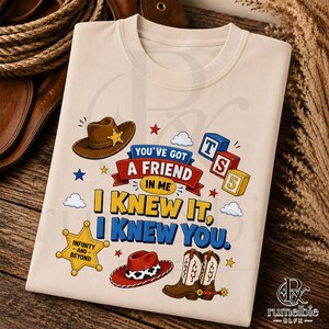 Puede incluir: Una camiseta beige con un estampado gr&aacute;fico que incluye un sombrero de vaquero marr&oacute;n, un sombrero rojo y blanco con estampado de vaca y botas de vaquero marrones. El texto dice: You've got a friend in me, I knew it, I knew you, Infinity and Beyond y TS5, con iconos de estrellas.